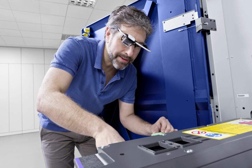 Technicien en train d'effectuer un acte de maintenance sur une imprimante.
