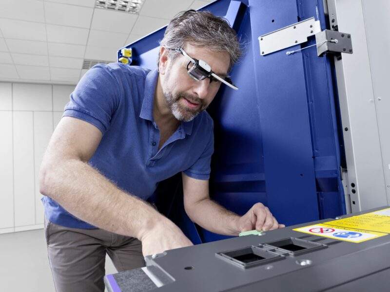Technicien en train d'effectuer un acte de maintenance sur une imprimante.